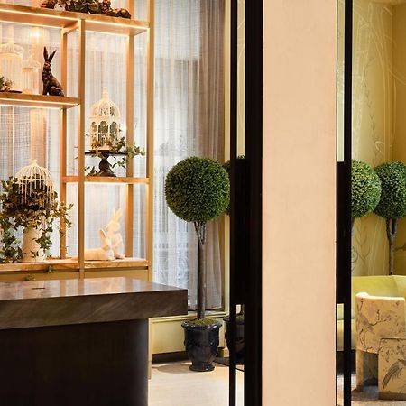 Park Lane New York酒店 外观 照片 The photo depicts a stylish interior space, likely a lobby or a waiting area. On the left side, there's a sleek black reception desk. Behind it, there is a decorative shelving unit with potted plants, small sculptures, and a few whimsical items, incl