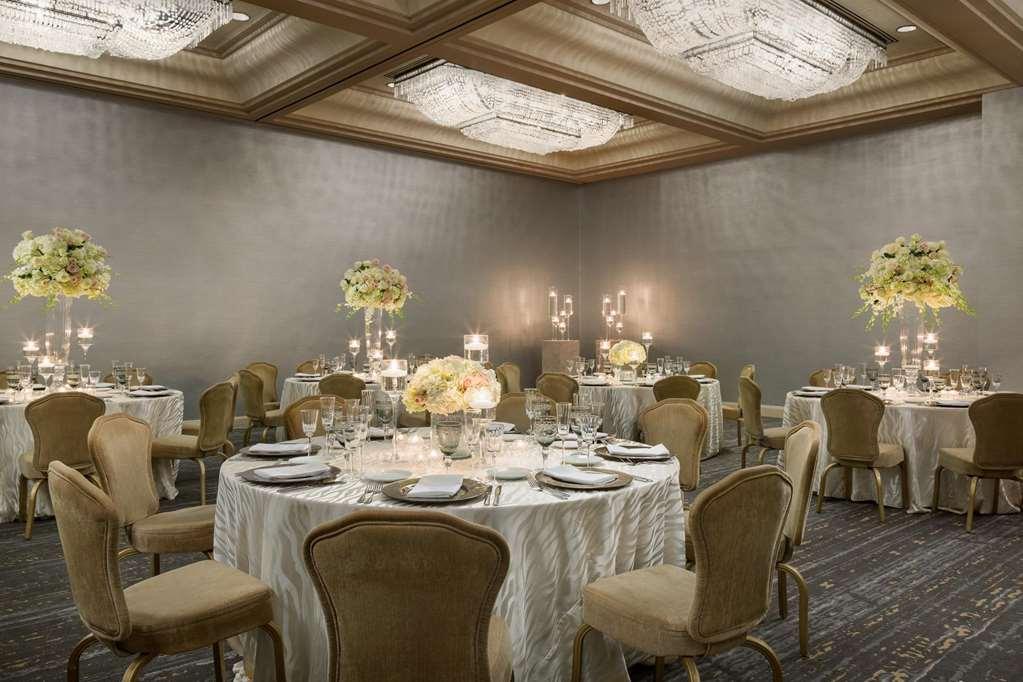 Park Lane New York酒店 餐厅 照片 The photo shows an elegant dining room or banquet hall. There are several round tables covered with white tablecloths, each set with fine dining ware including plates, glasses, and utensils. The tables are adorned with floral arrangements in light co