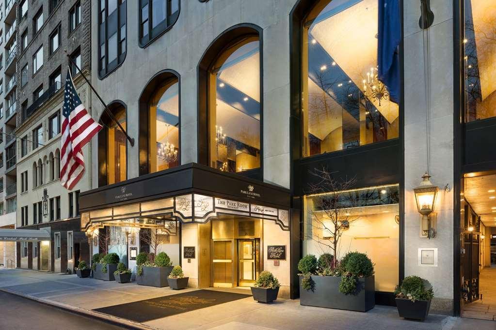 Park Lane New York酒店 外观 照片 The photo shows the exterior of a hotel, featuring a prominent entrance with large glass windows and a stylish facade. The building has a modern design with elegant architectural details and is accentuated by a series of large arches. A U.S. flag is 