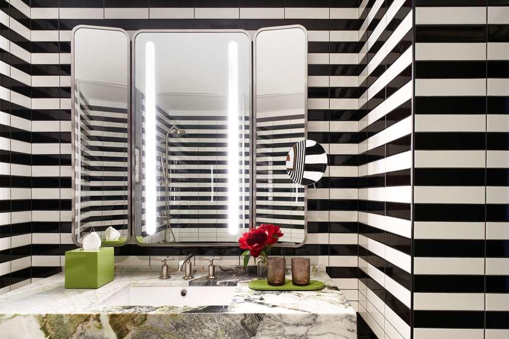 Park Lane New York酒店 外观 照片 The image shows a modern bathroom with a striking design. The walls are decorated with bold black and white stripes, creating a dramatic visual effect. There are large mirrors above the sink, framed in a sleek metallic finish, and bright, vertical LE