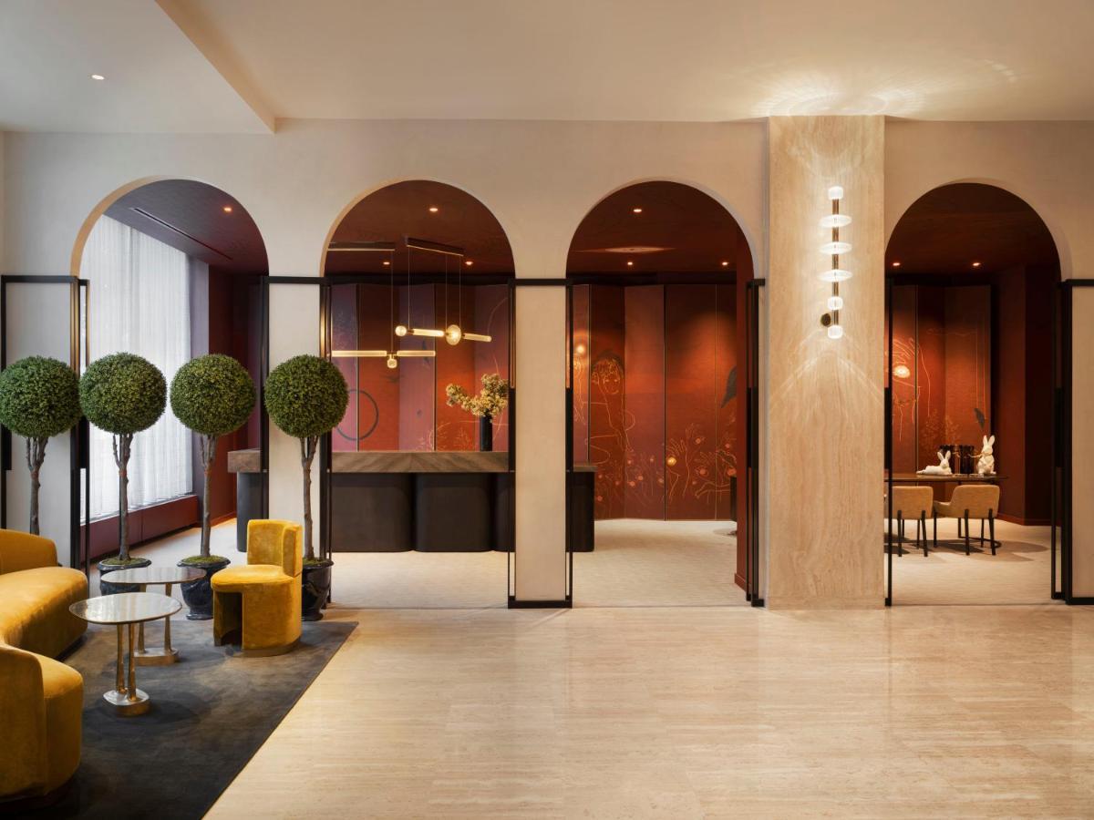 Park Lane New York酒店 外观 照片 The photo shows a modern and stylish lobby area. It features curved arches in the architecture, creating a sophisticated atmosphere. The walls are painted in a rich, warm hue, complemented by elegant lighting fixtures. There are small, round tables w