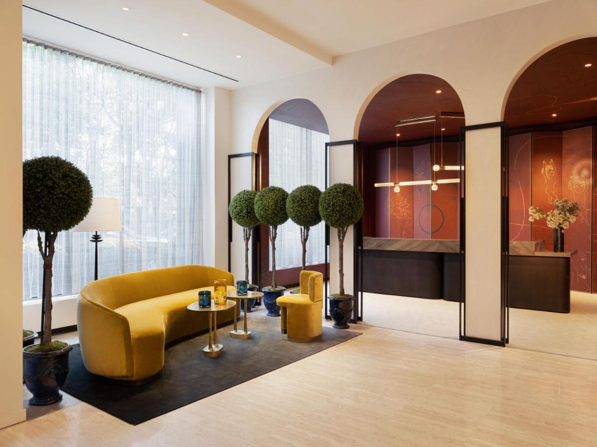 Park Lane New York酒店 外观 照片 The photo depicts a modern interior space, likely a lobby or lounge area. It features a stylish, curved yellow sofa complemented by two smaller yellow chairs. The floor is adorned with a dark rug, and there are small round tables with decorative item