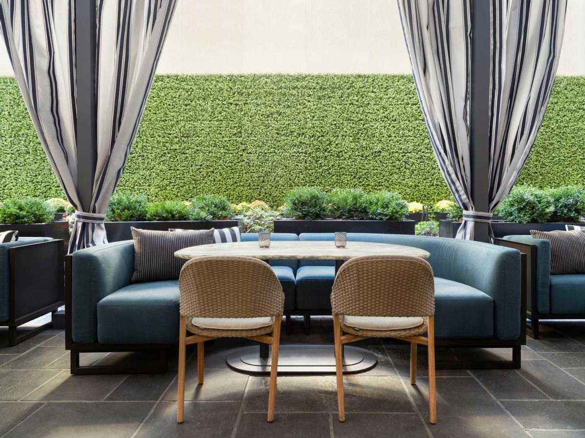 Park Lane New York酒店 外观 照片 The photo shows a modern outdoor seating area. There are two chairs positioned around a small table, with a plush blue sofa in the background. The sofa has cushions and is set against a backdrop of greenery, including potted plants or hedges. The are