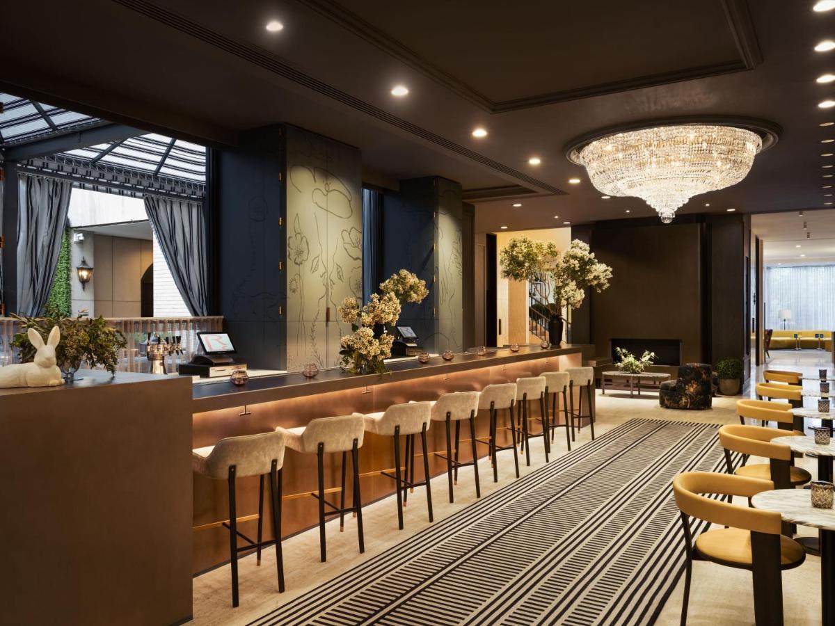 Park Lane New York酒店 外观 照片 The photo shows the interior of a stylish hotel lobby. There is a long reception bar with high stools, where guests likely check in or receive assistance. The decor features elegant lighting, including a large chandelier hanging from the ceiling. The