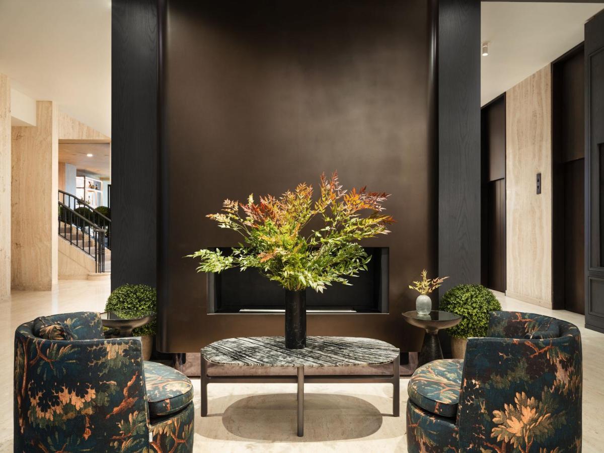 Park Lane New York酒店 外观 照片 The photo depicts a stylish interior space, likely a lobby or lounge area. In the center, there is a table adorned with a large floral arrangement featuring vibrant foliage. Surrounding the table are two upholstered chairs with a floral pattern that 