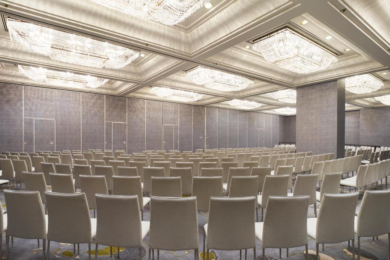 Park Lane New York酒店 外观 照片 The photo shows an empty conference room or event space. It features rows of light-colored chairs arranged in a neat pattern facing a front area. The room has a modern design, with elegant ceiling fixtures that include chandeliers, and the walls are 