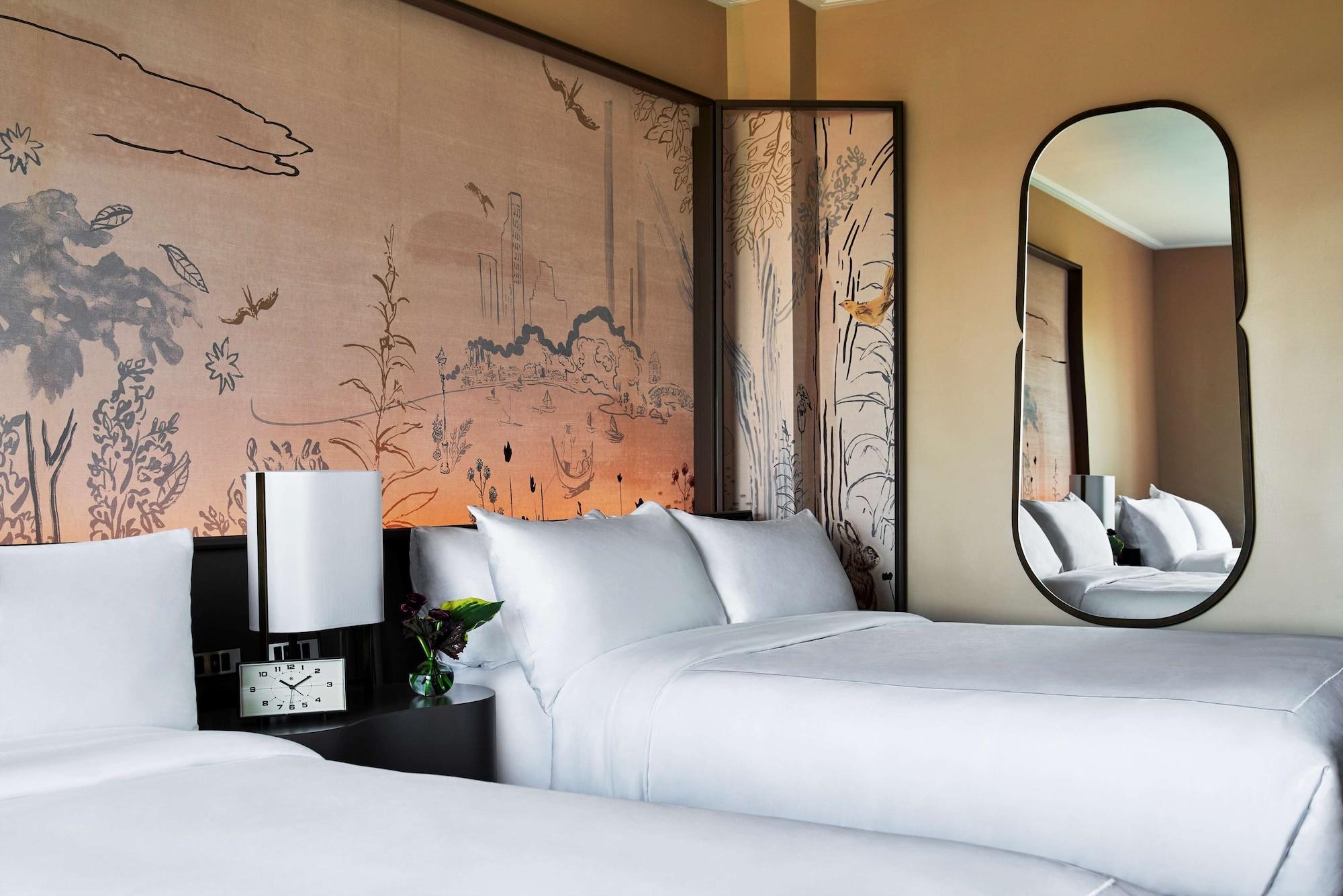 Park Lane New York酒店 外观 照片 The image shows a modern hotel room featuring two beds with white bedding. Behind the beds is a decorative wall with a soft, artistic design that includes landscapes and natural elements. There is a sleek, oval mirror on one side and a bedside table 