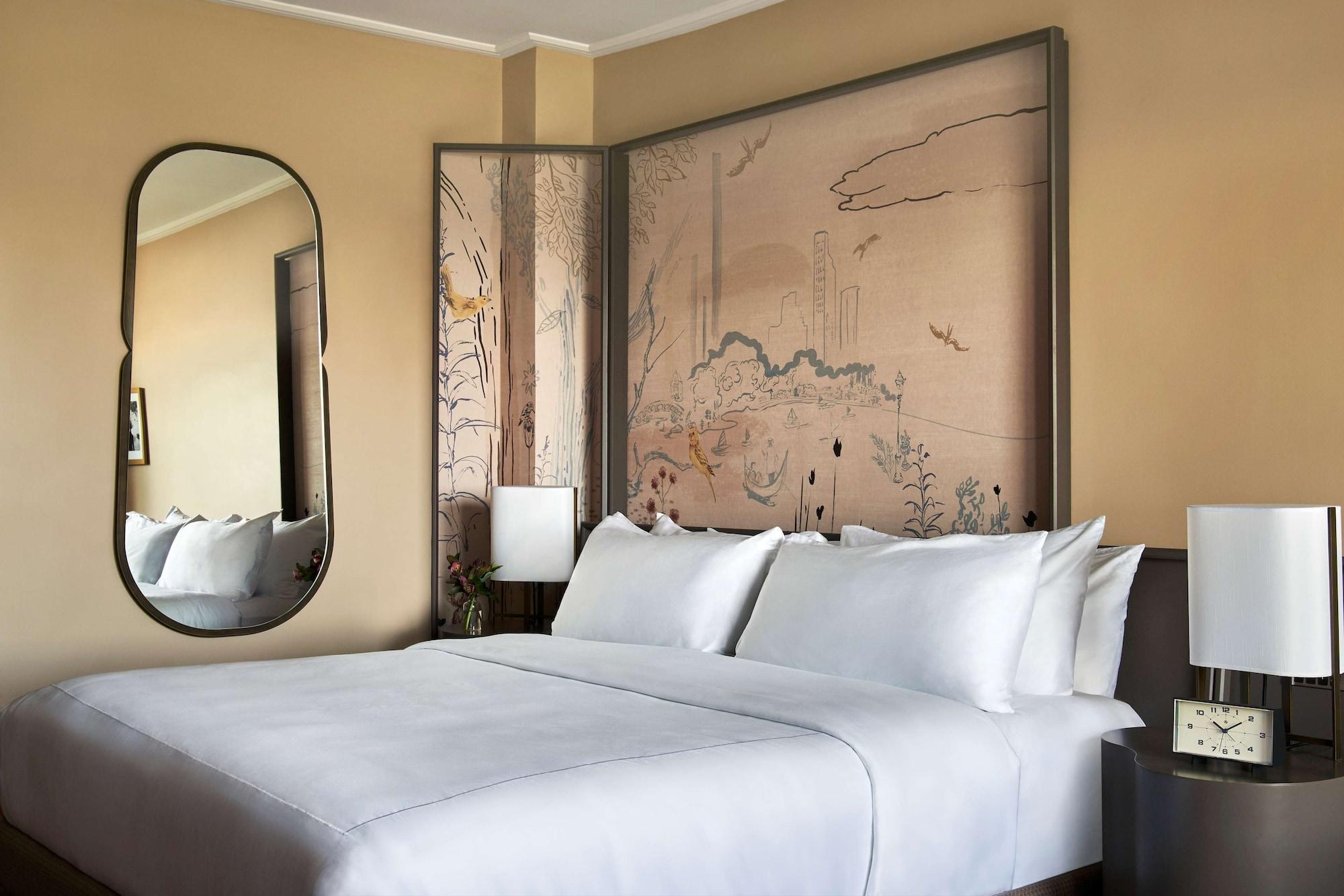 Park Lane New York酒店 外观 照片 The photo shows a modern bedroom with a light, neutral color scheme. There is a large bed with crisp white linens and multiple pillows. Behind the bed is an artistic feature that includes a painted wall mural, likely depicting nature or a serene land