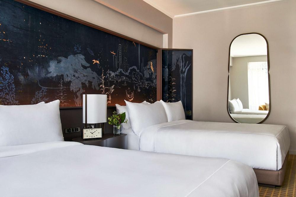 Park Lane New York酒店 外观 照片 The photo depicts a modern hotel room featuring two white beds with neatly arranged bedding. Behind the beds is an artistic wall with a dark, scenic mural, which adds a touch of elegance to the space. There is a bedside table with a clock and a small