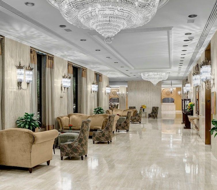 Park Lane New York酒店 外观 照片 The image shows an elegant hotel lobby or lounge area. It features a polished marble floor and is decorated with soft, neutral-colored walls. The space is illuminated by several large chandeliers hanging from the ceiling and sconces mounted on the wa