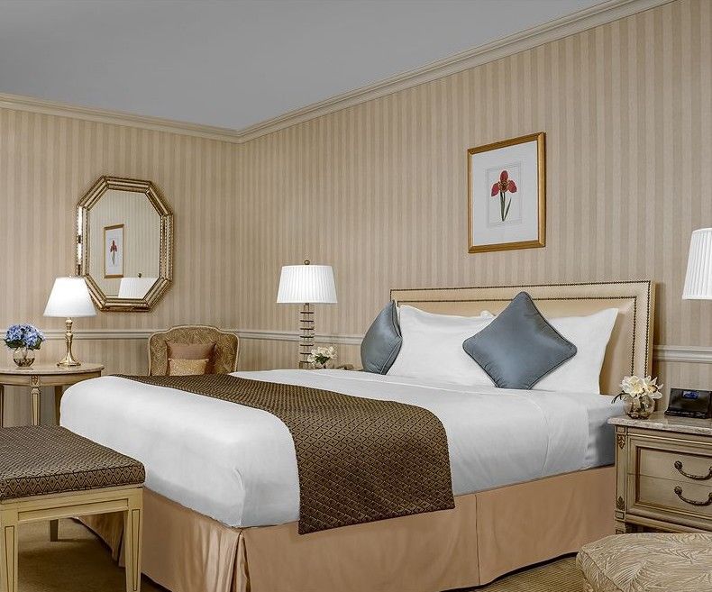 Park Lane New York酒店 外观 照片 The photo shows a well-decorated hotel room featuring a neatly made king-sized bed. The bed has a light-colored comforter with decorative pillows in shades of blue. On either side of the bed, there are bedside tables with lamps providing soft lightin