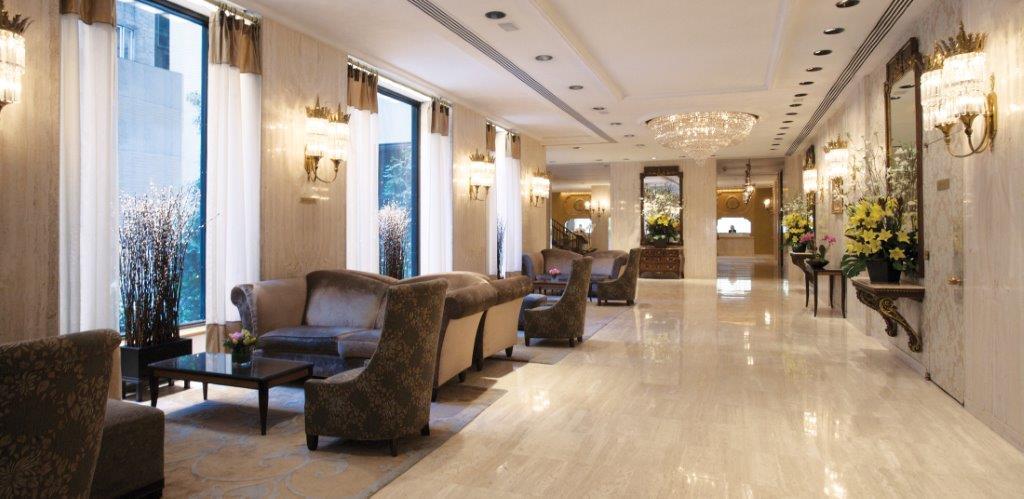 Park Lane New York酒店 外观 照片 The photo shows an elegant hotel lobby with a spacious and well-lit layout. The floors are marble, giving a polished appearance. On one side, there are several comfortable seating areas, including chairs and sofas arranged around small tables. Large 