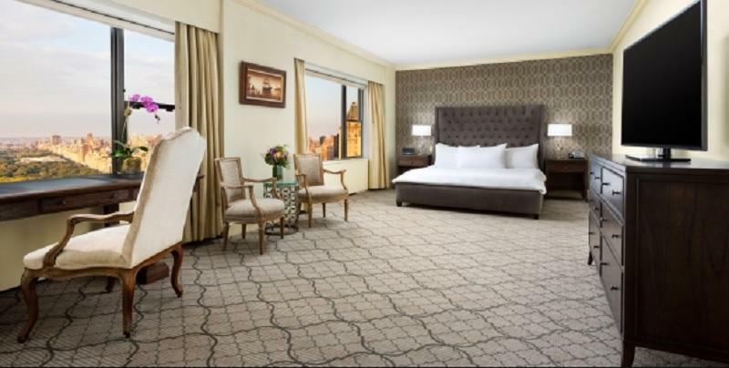 Park Lane New York酒店 外观 照片 The photo shows a spacious hotel room featuring a large bed with white bedding. There are two elegant chairs and a small table, likely used for seating or relaxation. The room has large windows with curtains that allow natural light to enter, and the