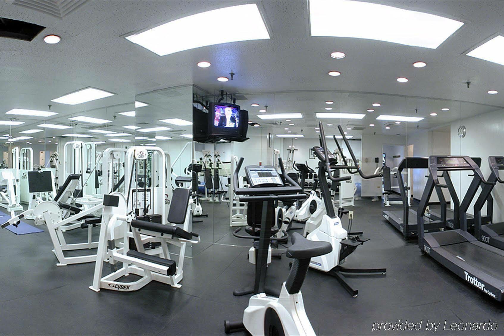 Park Lane New York酒店 设施 照片 The photo shows a modern gym or fitness center. The space features various exercise equipment, including treadmills, stationary bikes, and weight machines. There are also mirrors on the walls, which can make the area appear more spacious. A televisio